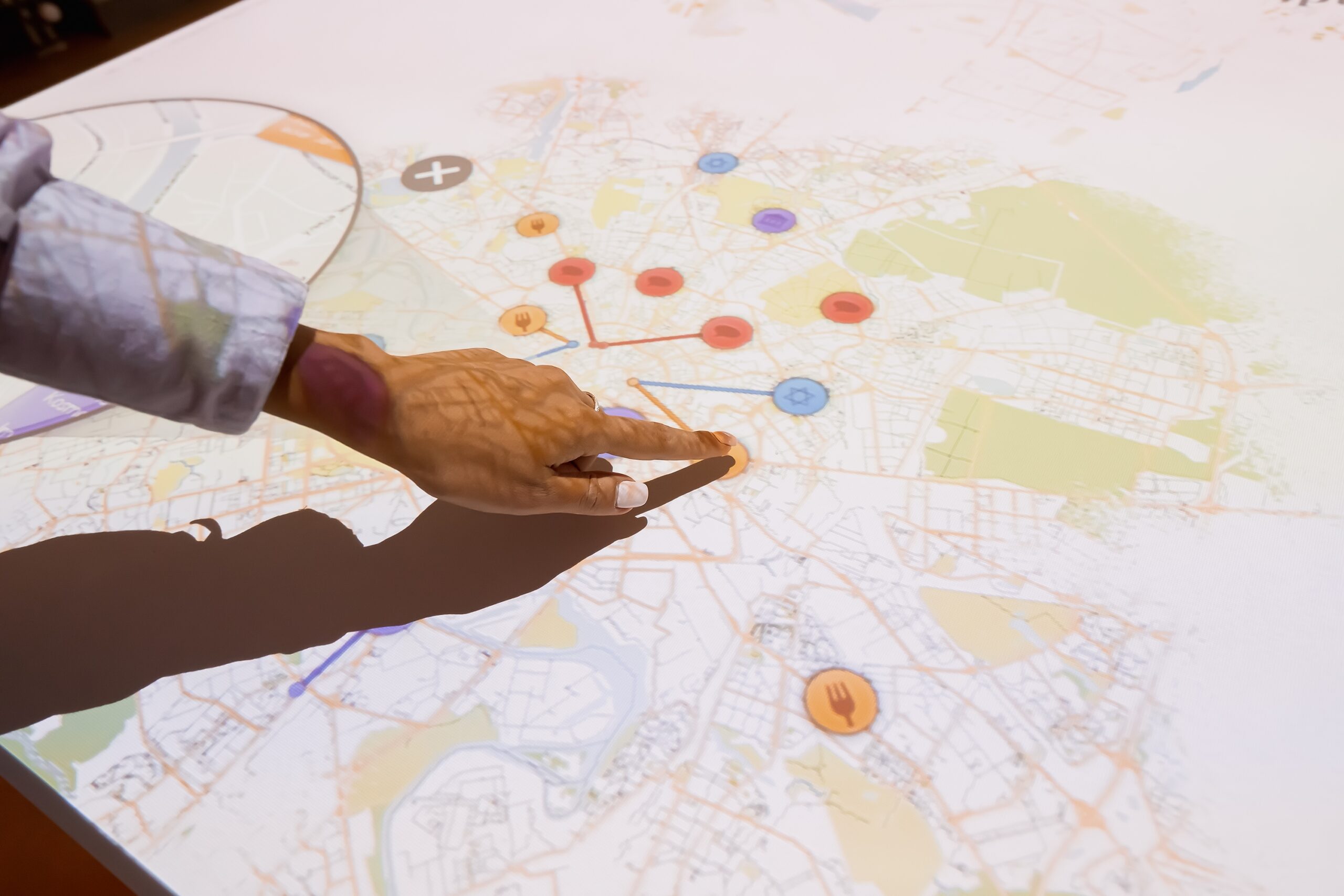 A person interacting with an interactive digital map projected on a table, illustrating immersive technology applications for events and real estate marketing.
