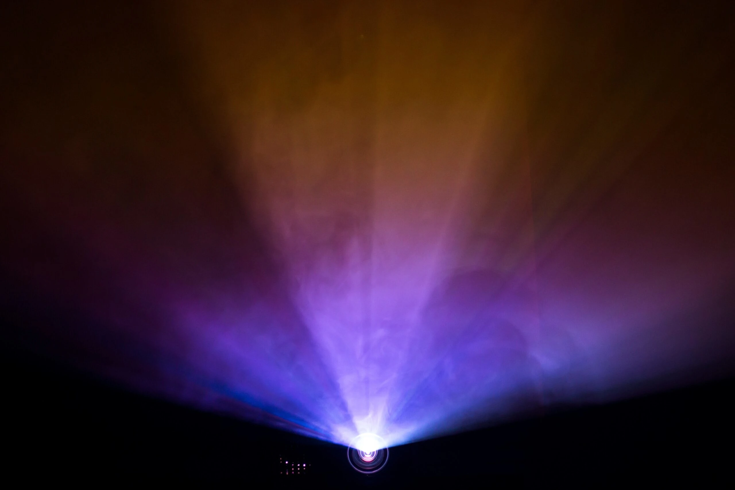 A beam of vibrant light in shades of purple and gold emanating from a projector, symbolizing a digital interactive experience. The glowing effect creates an immersive and captivating atmosphere, perfect for events or presentations that rely on advanced visual technologies to engage audiences.