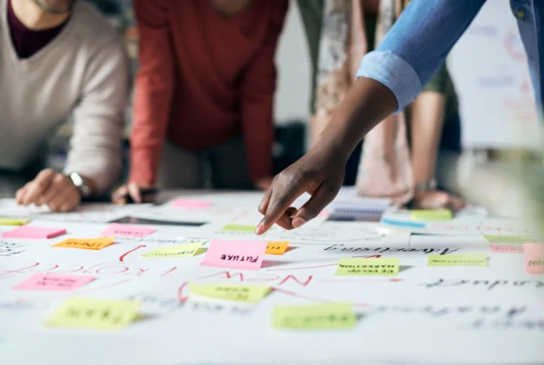 A close-up of a creative planning session, with team members collaborating over a table filled with colorful sticky notes labeled with terms like "future" and "innovation." The scene reflects the strategic mapping of the customer journey, essential for designing an interactive showroom and implementing effective experiential marketing strategies that engage audiences and drive meaningful brand interactions.