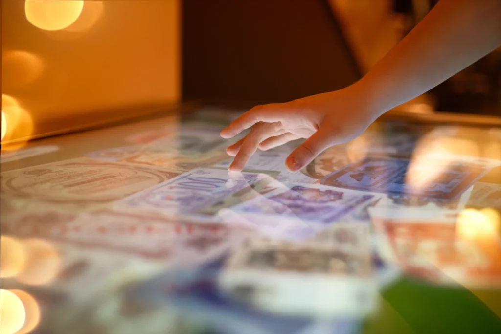 A close-up of a person's hand interacting with a touchscreen interface, illustrating the core concept of immersive solutions and experiential technology. The display features vibrant, layered content, capturing the essence of user engagement and multi-sensory interaction in modern digital environments—perfect for museums, exhibitions, and retail spaces.