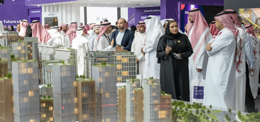 Cityscape Global attendees in traditional Saudi dress examining detailed scale models of future Riyadh real-estate developments.