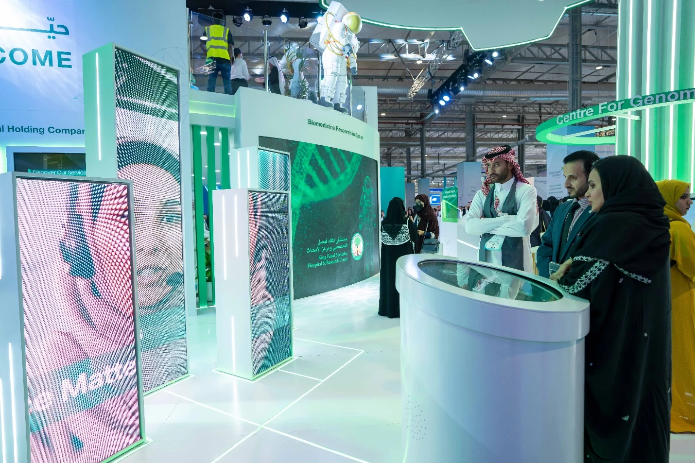 Interactive green LED booth at Global Health Exhibition in Riyadh, with visitors exploring genomics research displays and touchscreens.
