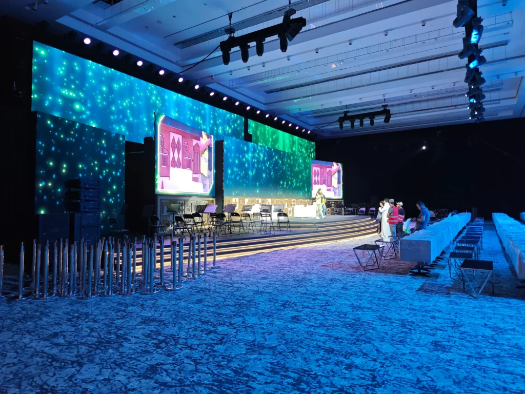 Immersive blue-lit ballroom with LED star-field backdrop and stepped stage in setup, showcasing VIP event solutions with projection mapping and luxury seating.
