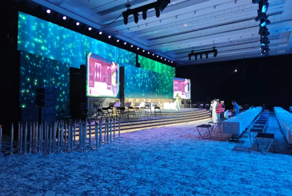 Immersive blue-lit ballroom with LED star-field backdrop and stepped stage in setup, showcasing VIP event solutions with projection mapping and luxury seating.