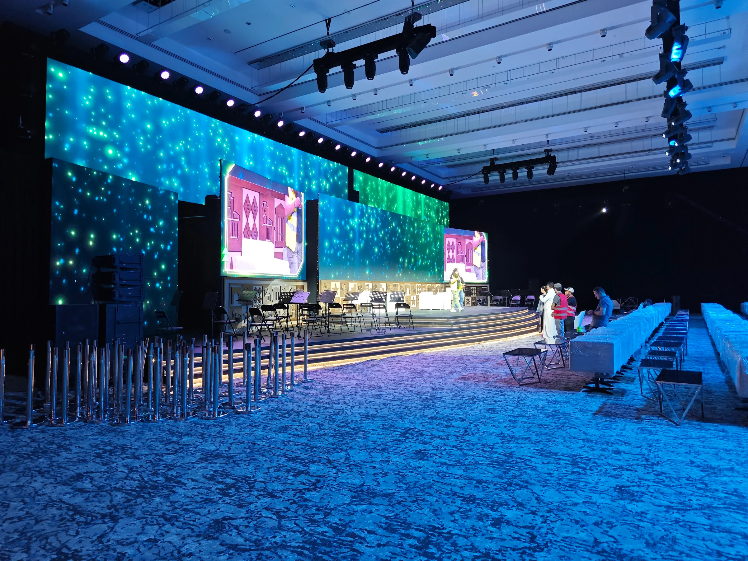 Immersive blue-lit ballroom with LED star-field backdrop and stepped stage in setup, showcasing VIP event solutions with projection mapping and luxury seating.