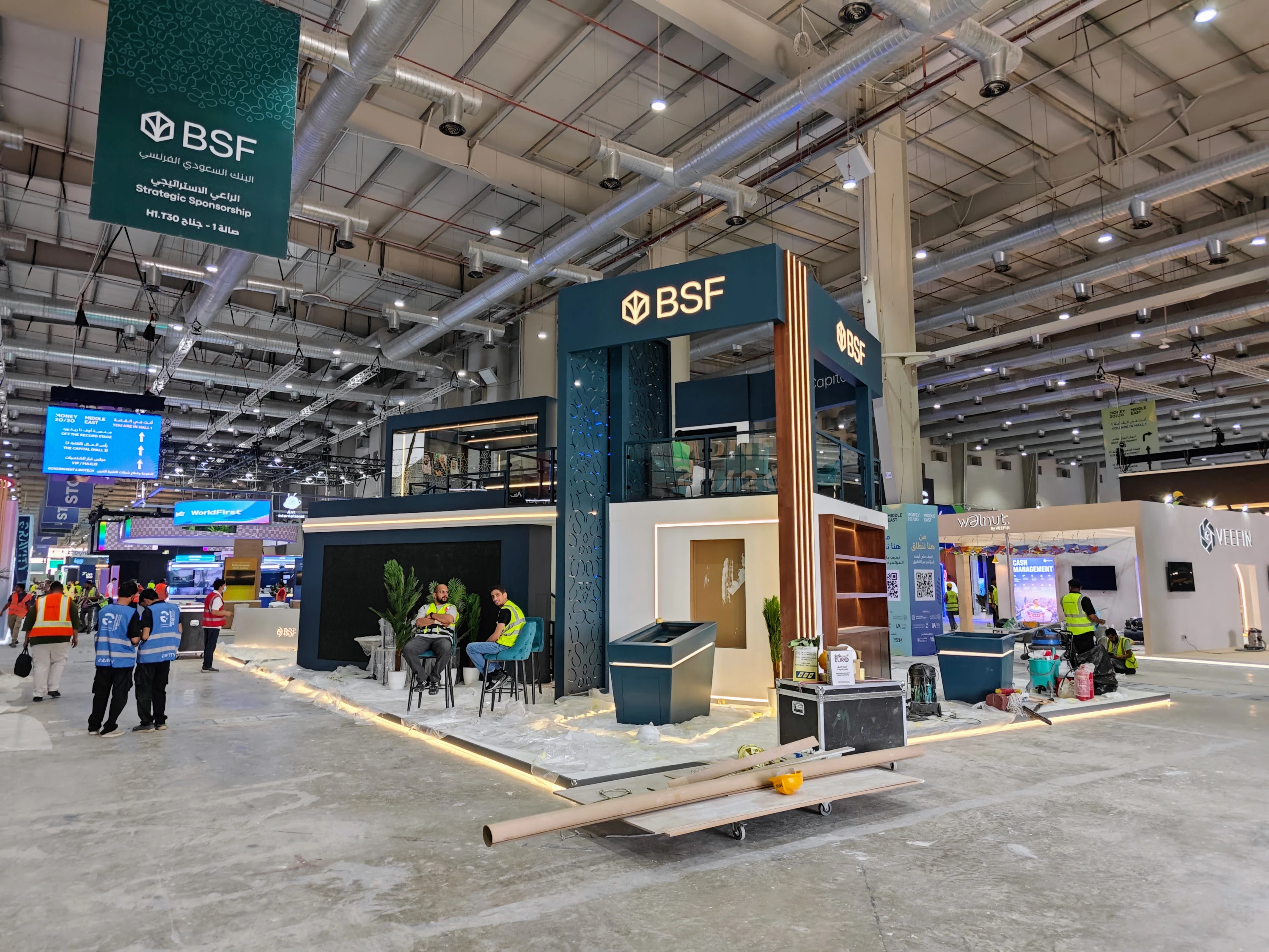 Angled view of the BSF stand under construction signage, mezzanine lounge, and crew preparing the booth before Money20/20 Riyadh opening.