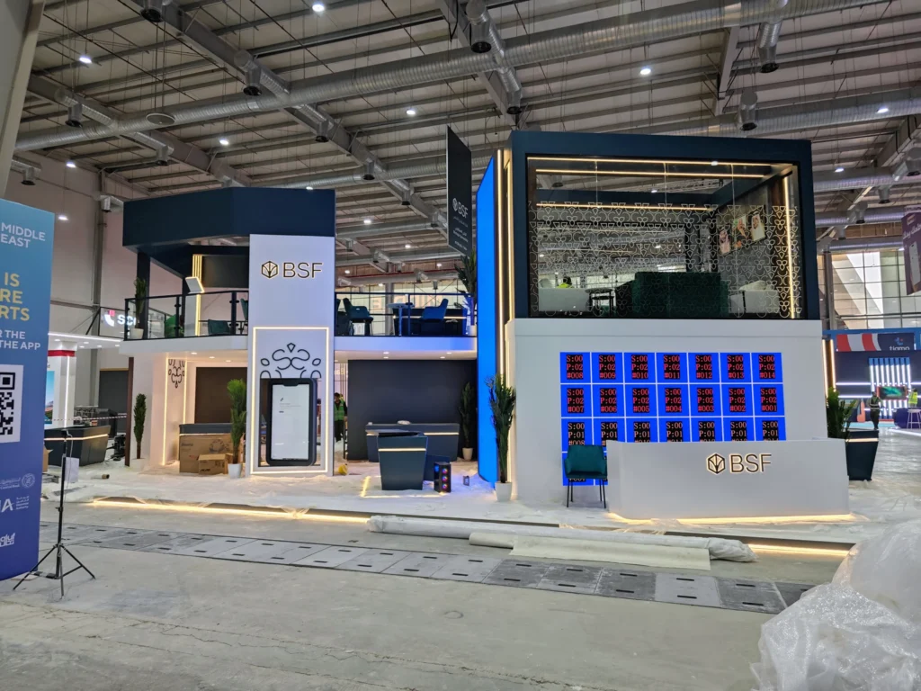 Front view of the two-level BSF stand under installation, mobile app screen frame and LED tests visible at Money20/20 Riyadh.