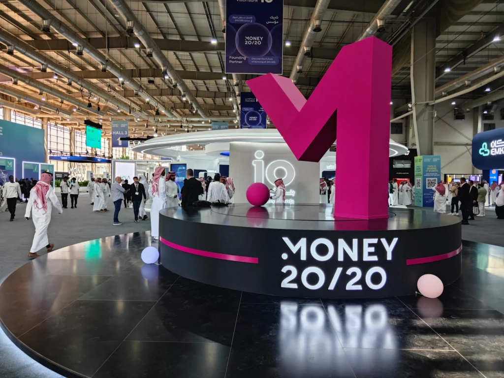 Money20/20 Riyadh exhibition floor with large ‘M’ landmark busy fintech show environment.