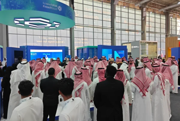 Crowd gathered at the Fintech Saudi stand during a live presentation, surrounded by digital screens and branding in a busy exhibition hall.