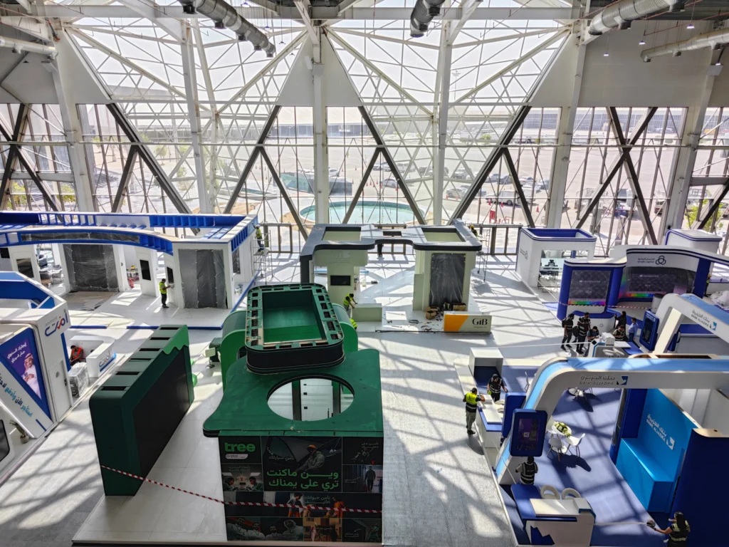 Overhead view of a large exhibition hall during build-up with modular booth structures—illustrating scalable, repeatable booth systems for 2026.