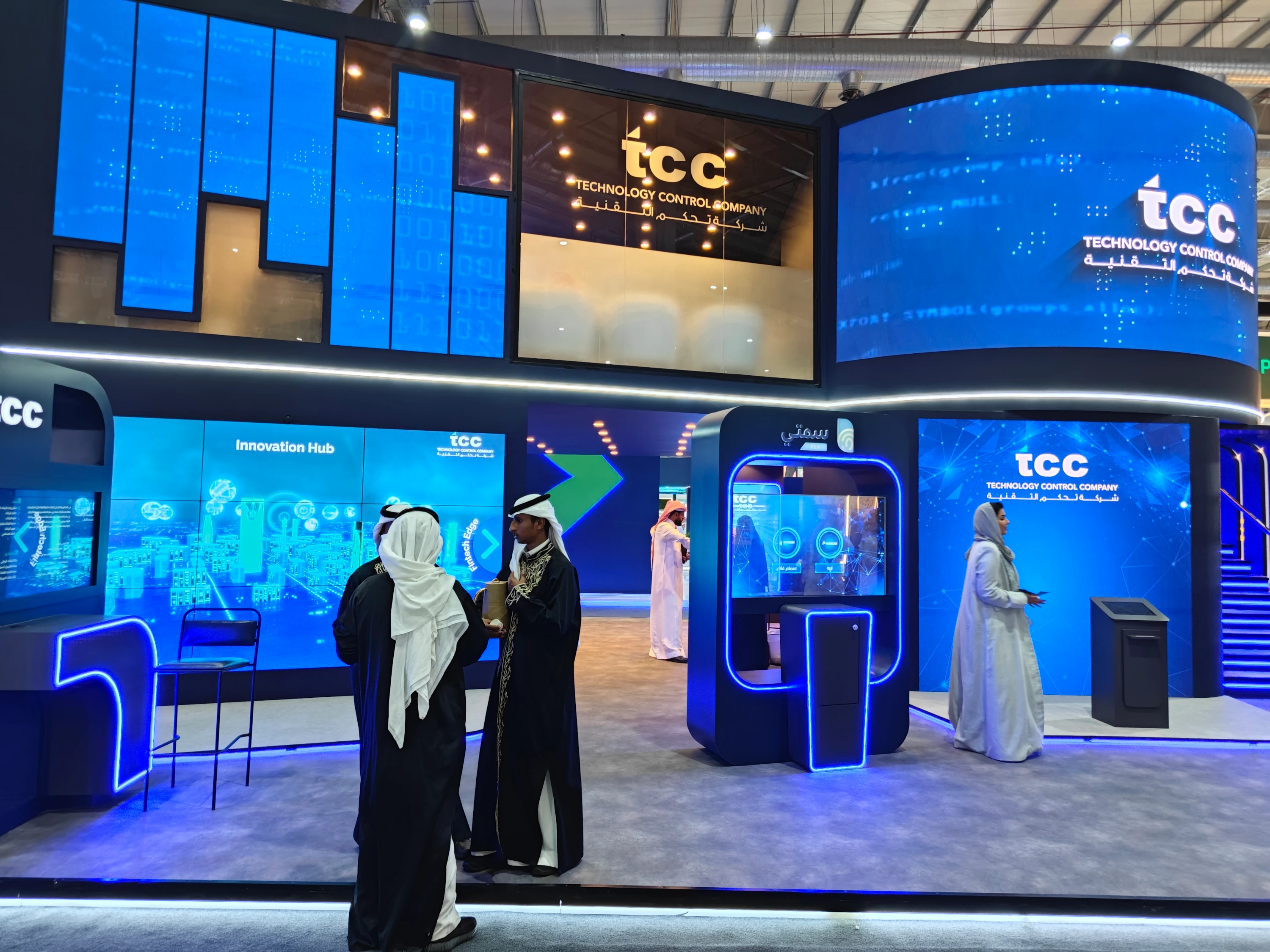 TCC exhibition booth with curved LED screens, modular video panels, and a lit interactive kiosk—AV-as-platform design built for reliability and visibility.